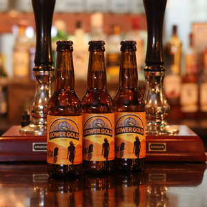 Three Gower Gold beer 330ml bottles placed on a bar